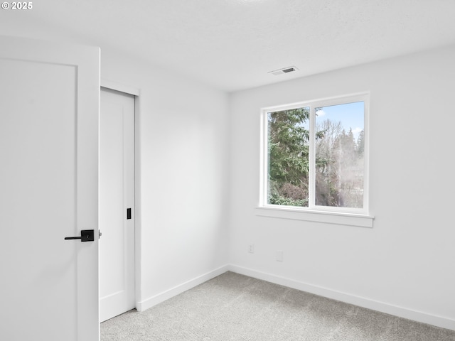 unfurnished bedroom featuring visible vents, baseboards, light colored carpet, a textured ceiling, and a closet