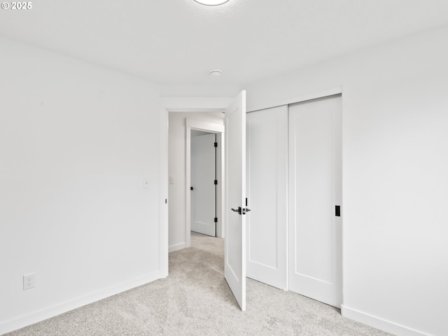 unfurnished bedroom featuring baseboards, a closet, and light colored carpet