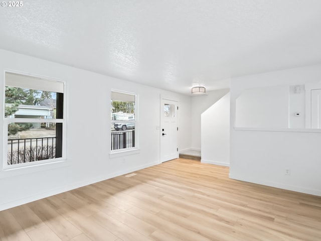 interior space featuring light wood-style floors, baseboards, and a textured ceiling