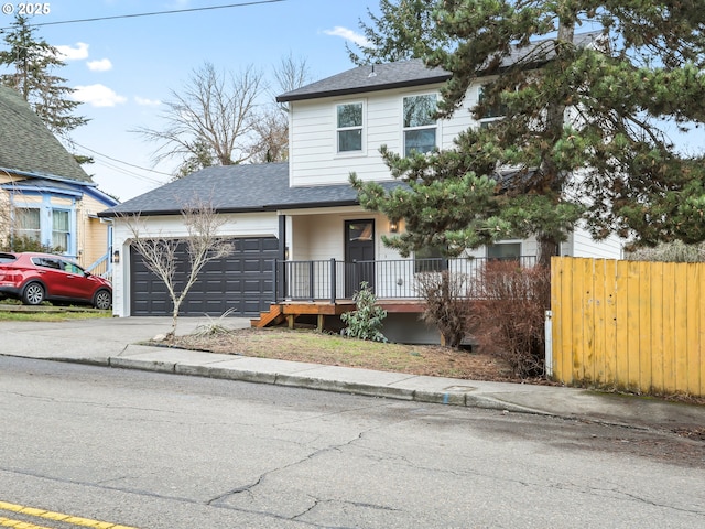 traditional home featuring a garage, driveway, a shingled roof, and fence