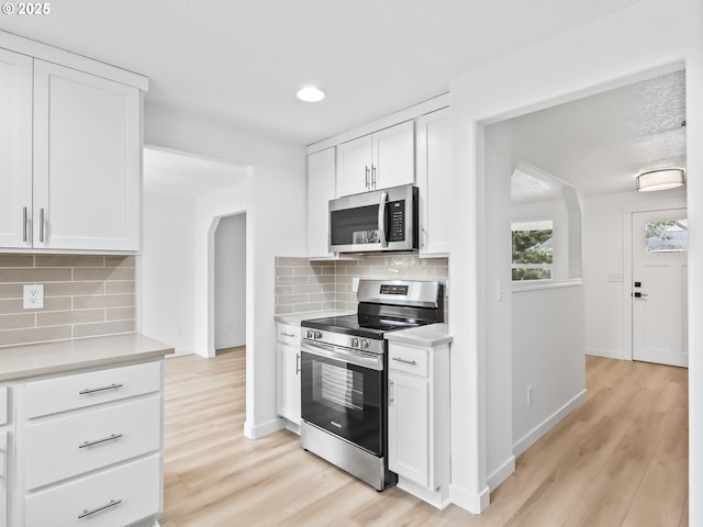 kitchen featuring appliances with stainless steel finishes, light countertops, light wood finished floors, and white cabinetry