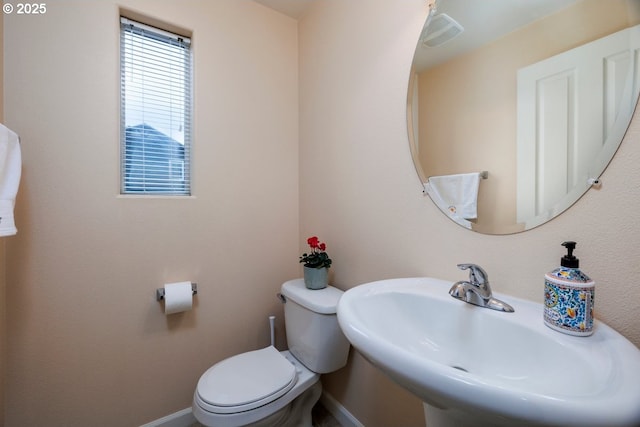 half bathroom with a sink, baseboards, and toilet