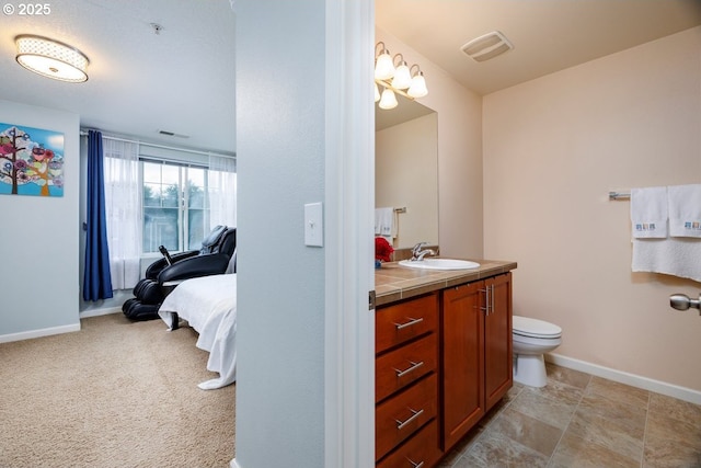 ensuite bathroom with baseboards, vanity, and toilet