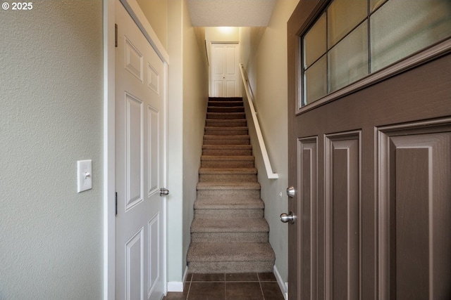 stairway with baseboards and tile patterned flooring