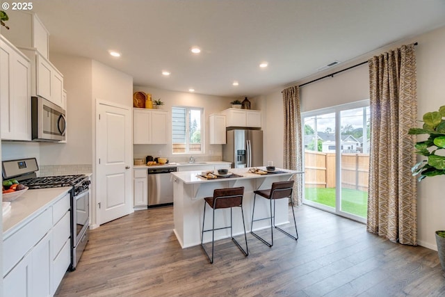 kitchen featuring sink, light wood-type flooring, white cabinetry, a kitchen island, and stainless steel appliances