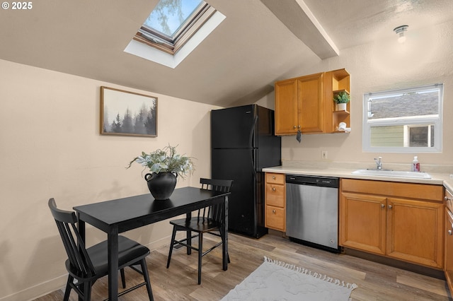 kitchen with vaulted ceiling, dishwasher, sink, black fridge, and light wood-type flooring