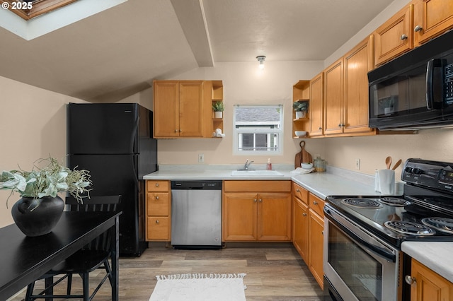 kitchen with lofted ceiling with skylight, sink, light wood-type flooring, and black appliances