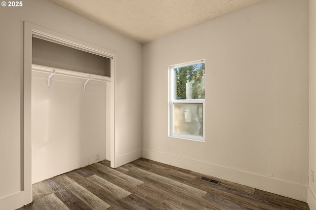 unfurnished bedroom with dark hardwood / wood-style flooring, a textured ceiling, and a closet