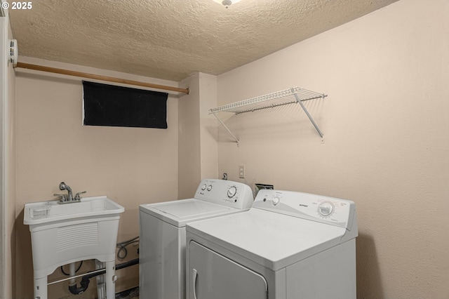 clothes washing area with sink, washer and clothes dryer, and a textured ceiling