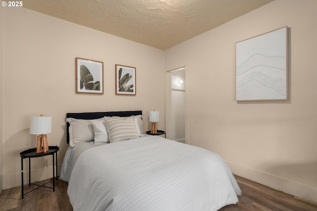 bedroom with a textured ceiling and dark hardwood / wood-style flooring