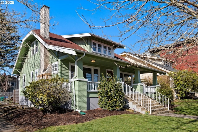 view of front of house with covered porch, a chimney, and a front yard