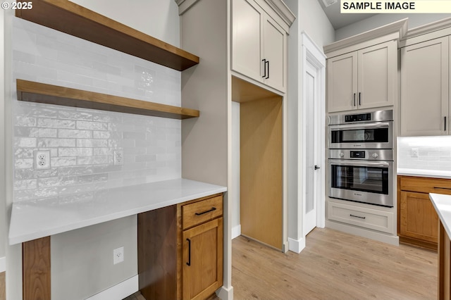 kitchen with backsplash, double oven, and light hardwood / wood-style flooring