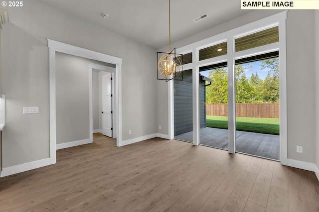 unfurnished dining area featuring hardwood / wood-style flooring and a notable chandelier