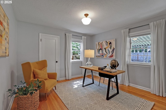office space featuring a textured ceiling, light wood-style floors, and baseboards
