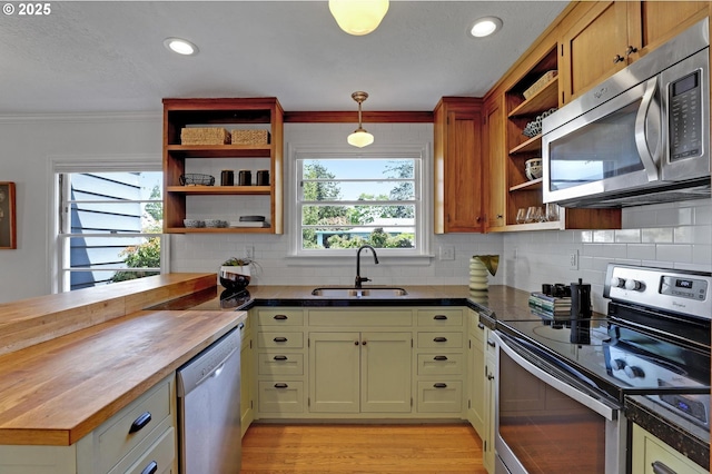 kitchen featuring tasteful backsplash, butcher block counters, open shelves, appliances with stainless steel finishes, and a sink