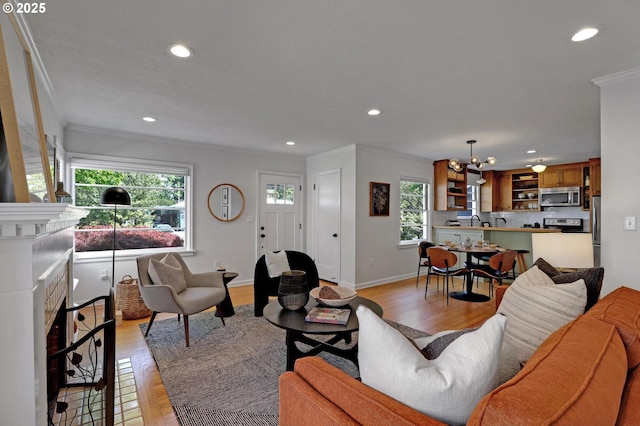 living area featuring recessed lighting, ornamental molding, an inviting chandelier, and light wood finished floors