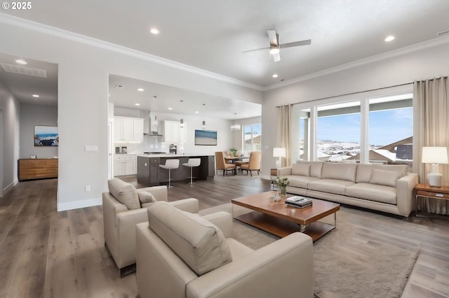 living room with light hardwood / wood-style floors, ceiling fan, and ornamental molding