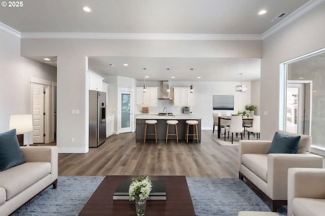 living room with sink, dark wood-type flooring, a notable chandelier, and crown molding