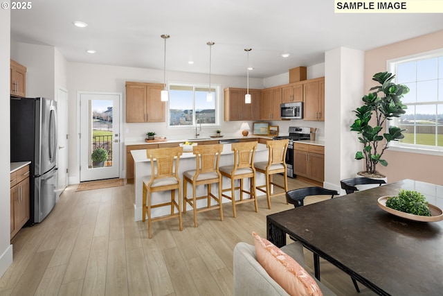 kitchen featuring a center island, a breakfast bar area, light countertops, light wood-style flooring, and stainless steel appliances