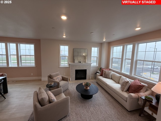 living room featuring recessed lighting, baseboards, a tiled fireplace, and light wood finished floors