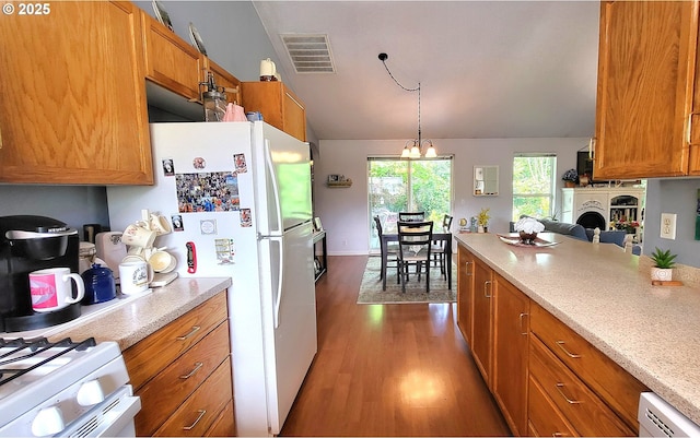 kitchen with dark wood finished floors, brown cabinetry, lofted ceiling, pendant lighting, and a chandelier
