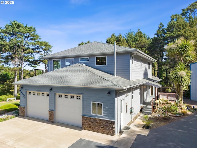 5220 SW Neal Ave, Waldport, OR 97394 - view of home's exterior featuring concrete driveway, a garage, a wooden deck, stone siding, and roof with shingles