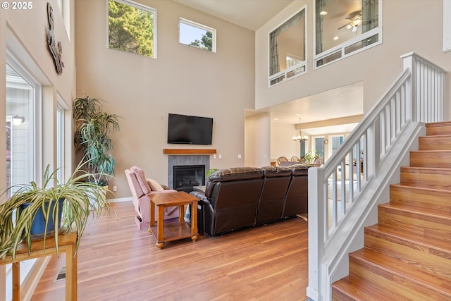 5220 SW Neal Ave, Waldport, OR 97394 - living room featuring light wood finished floors, stairway, a high ceiling, a glass covered fireplace, and baseboards