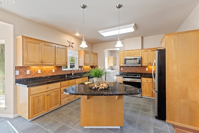 5220 SW Neal Ave, Waldport, OR 97394 - kitchen with appliances with stainless steel finishes, a sink, washer and clothes dryer, a center island, and decorative backsplash
