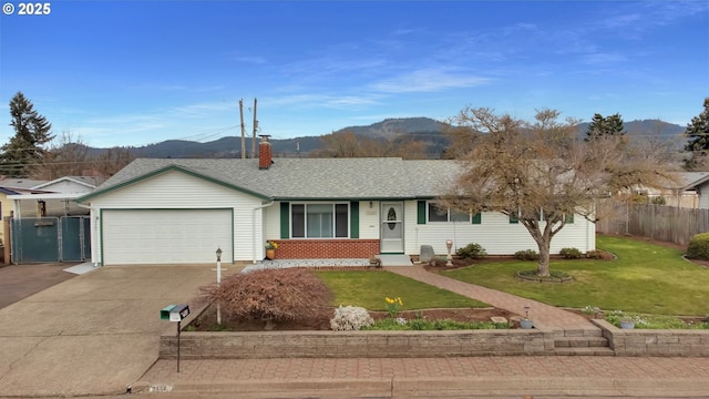 ranch-style home featuring fence, concrete driveway, a front yard, a garage, and a mountain view