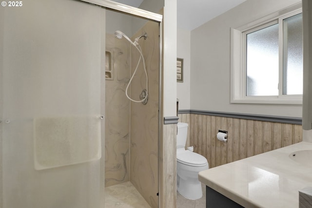 bathroom featuring a wainscoted wall, wood walls, toilet, a stall shower, and vanity