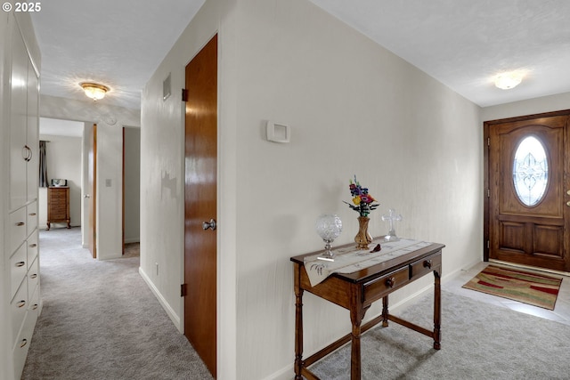 foyer entrance with baseboards and light carpet