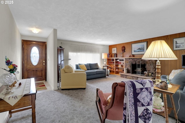 living room featuring wooden walls, a fireplace, carpet floors, and a textured ceiling