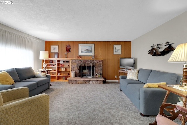 carpeted living room featuring a textured ceiling, a stone fireplace, and wooden walls