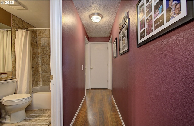 hallway with wood-type flooring and a textured ceiling