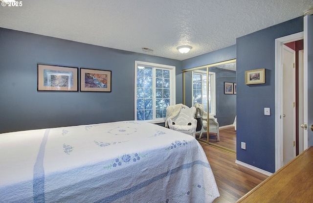 bedroom featuring wood-type flooring, a closet, and a textured ceiling