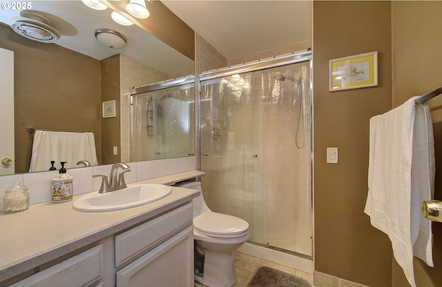 bathroom with tile patterned floors, vanity, toilet, and a shower with shower door