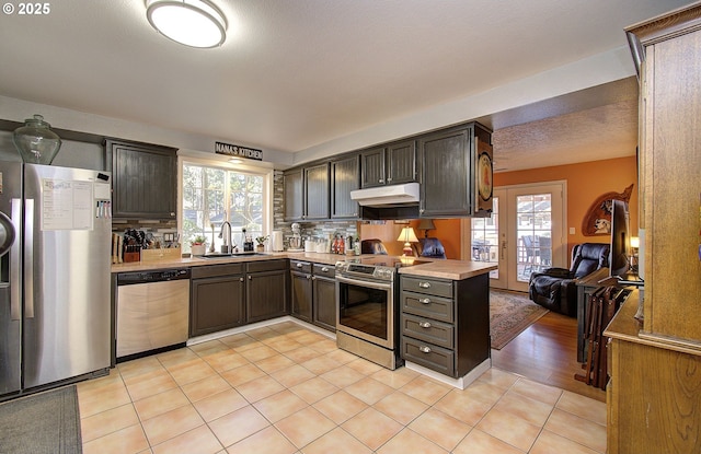 kitchen featuring light tile patterned flooring, appliances with stainless steel finishes, tasteful backsplash, sink, and dark brown cabinetry