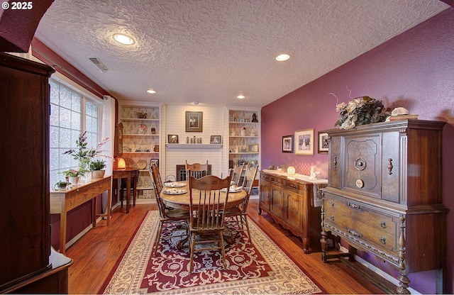 dining space with hardwood / wood-style flooring, a textured ceiling, and built in shelves