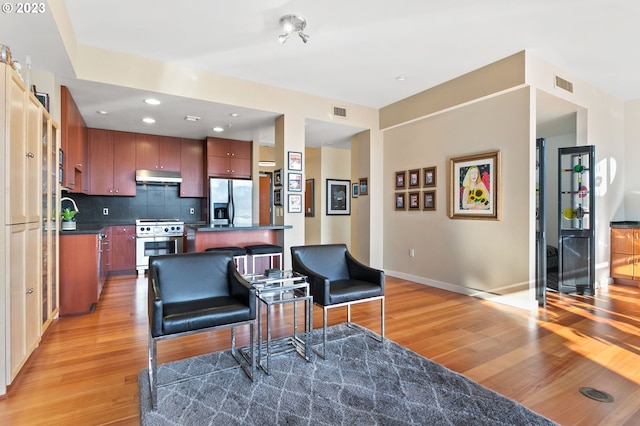 1025 NW Couch St Unit 613, Portland, OR 97209 - kitchen with light wood-type flooring, dark countertops, under cabinet range hood, visible vents, and appliances with stainless steel finishes