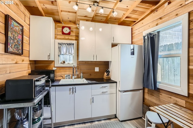 kitchen with freestanding refrigerator, wooden ceiling, and wooden walls