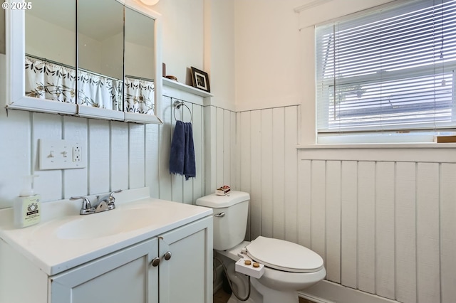 bathroom featuring toilet, vanity, and wainscoting