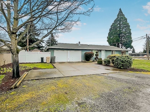 view of front of house featuring a garage, driveway, a front lawn, and fence