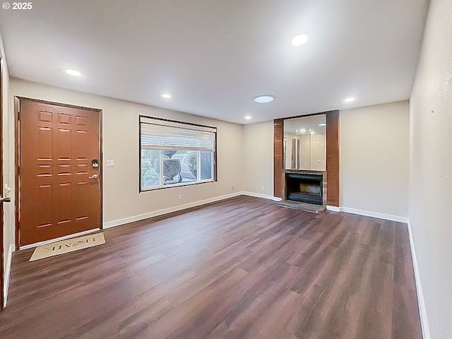 unfurnished living room with dark wood-type flooring, recessed lighting, a fireplace, and baseboards