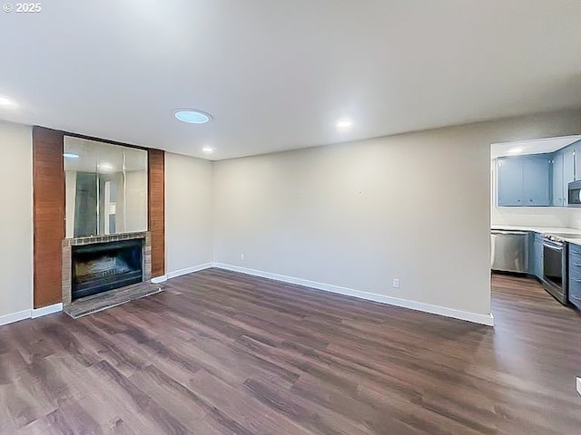 unfurnished living room with a fireplace, baseboards, and dark wood-style flooring