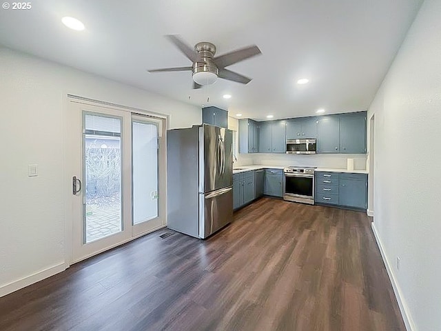 kitchen featuring stainless steel appliances, light countertops, dark wood-type flooring, a sink, and baseboards