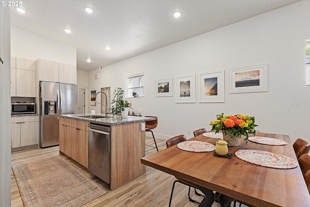 1905 2nd St, Baker City, OR 97814 - kitchen with stainless steel appliances, a sink, modern cabinets, a kitchen island with sink, and light wood-style flooring