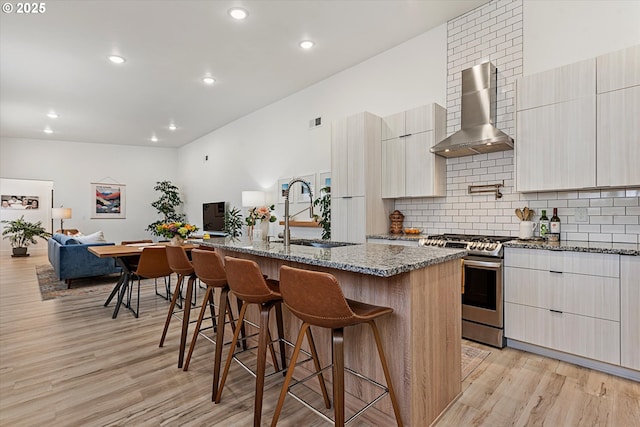1905 2nd St, Baker City, OR 97814 - kitchen featuring stainless steel gas range oven, a sink, wall chimney range hood, modern cabinets, and a breakfast bar area