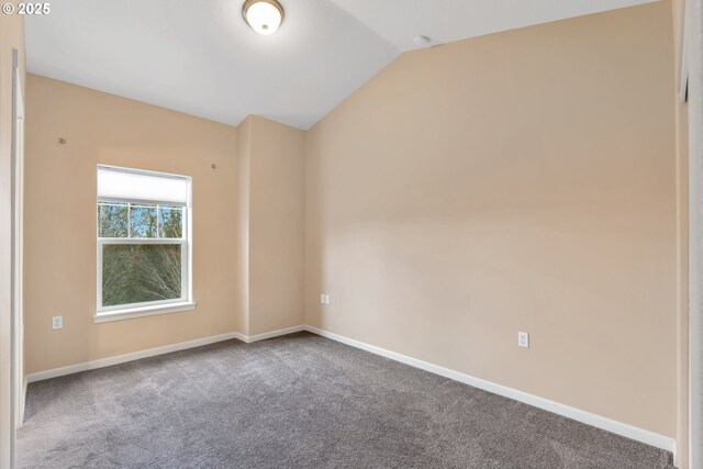 carpeted spare room with baseboards and vaulted ceiling