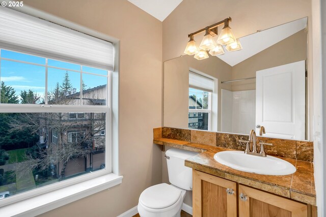 bathroom with baseboards, an inviting chandelier, toilet, vanity, and vaulted ceiling