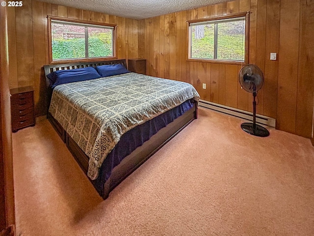 bedroom featuring a baseboard heating unit, multiple windows, a textured ceiling, and carpet flooring